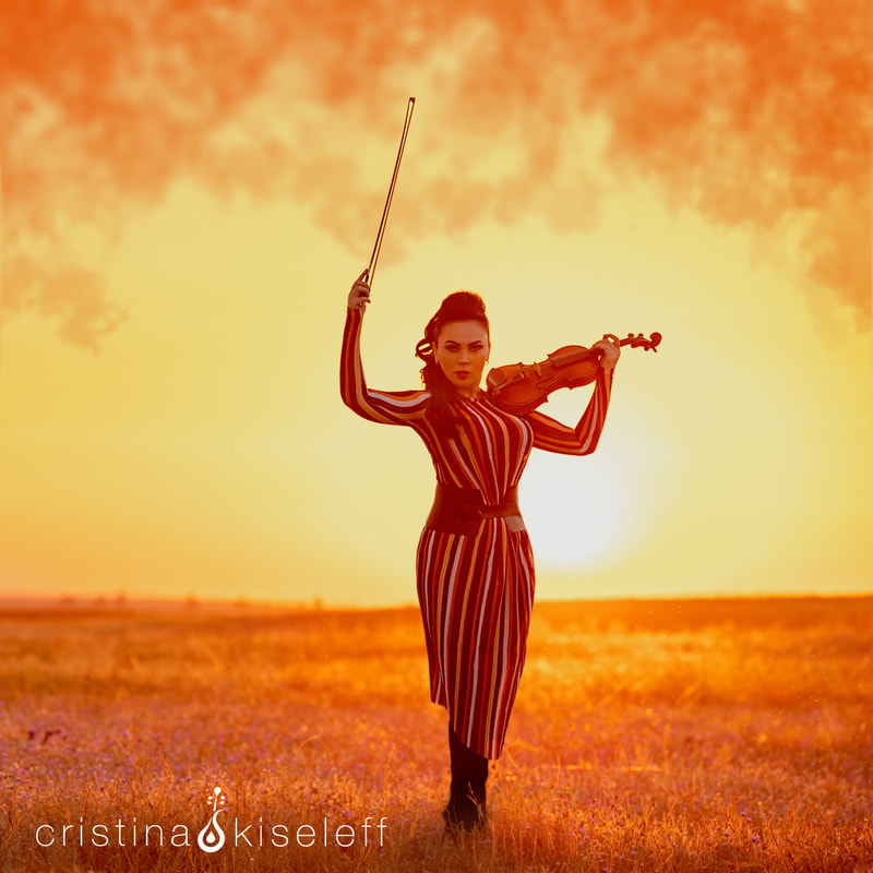 Cristina Kiseleff Playing a classical violin on a orange sunset background with an oriental dress