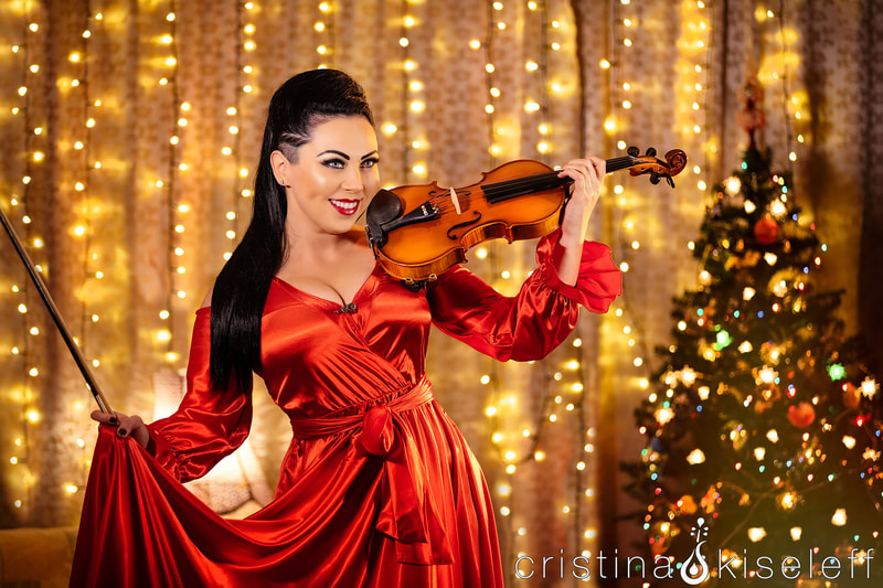 Cristina Kiseleff Electric Violinist in a satin red dress performing live at a  Christmas Party with a Xmas tree and lights