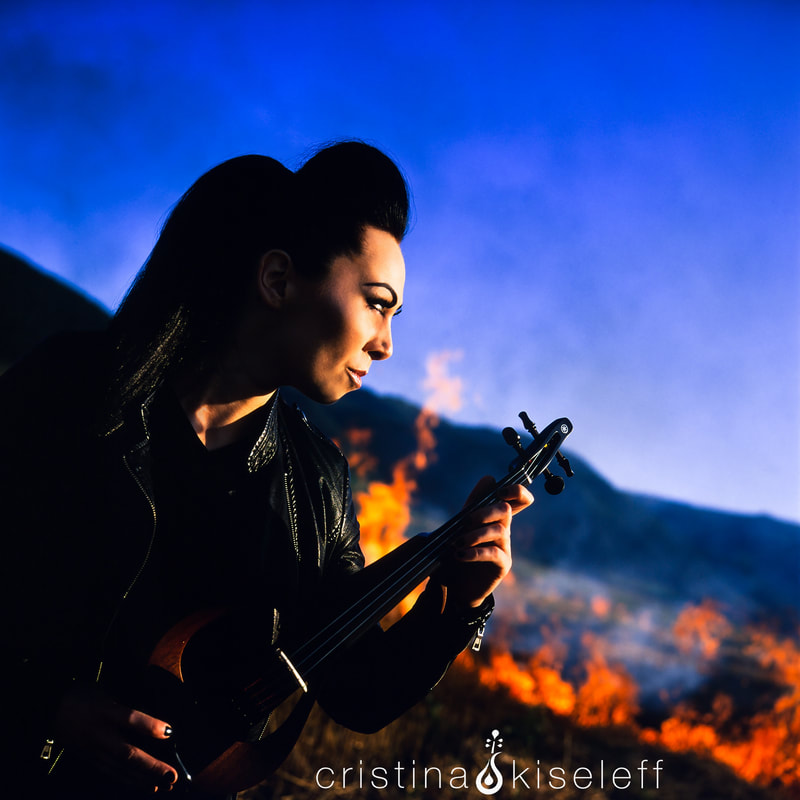 Cristina Kiseleff Electric Warrior Violinist Epic Portrait performing in front of red flames while the background is on fire